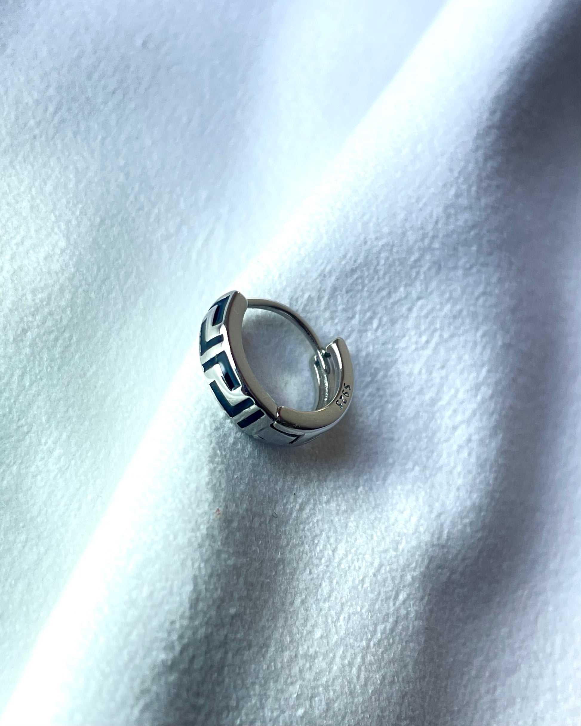 925 Silver hoop earring with geometric design on a white fabric background